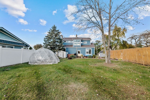 back of property with a yard and a shed