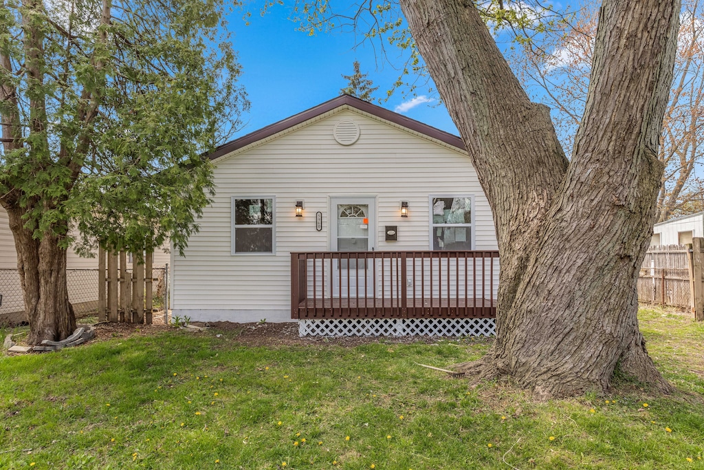 back of property with a lawn and a deck