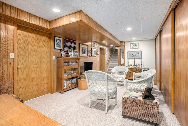 interior space with carpet, a paneled ceiling, and wooden walls