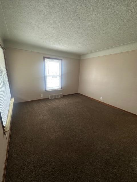 carpeted empty room with a textured ceiling