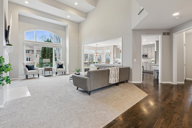 living room with dark hardwood / wood-style flooring, a high ceiling, and a notable chandelier