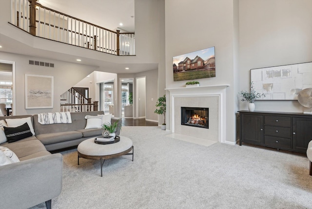 carpeted living room with plenty of natural light, a towering ceiling, and a fireplace