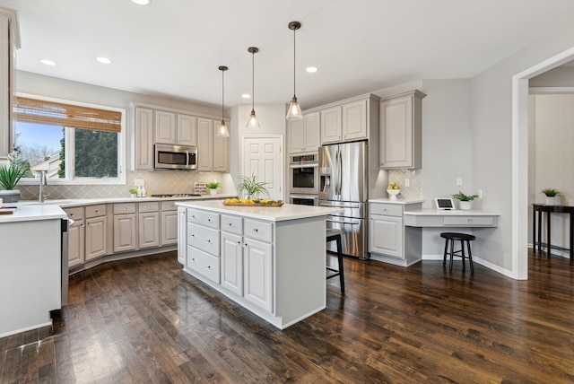 kitchen featuring dark wood-type flooring, hanging light fixtures, stainless steel appliances, a kitchen breakfast bar, and a kitchen island