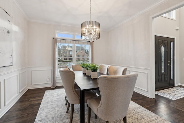 dining space with dark hardwood / wood-style flooring, ornamental molding, and an inviting chandelier