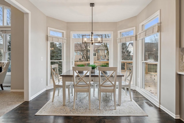 dining area featuring dark wood-type flooring and a notable chandelier