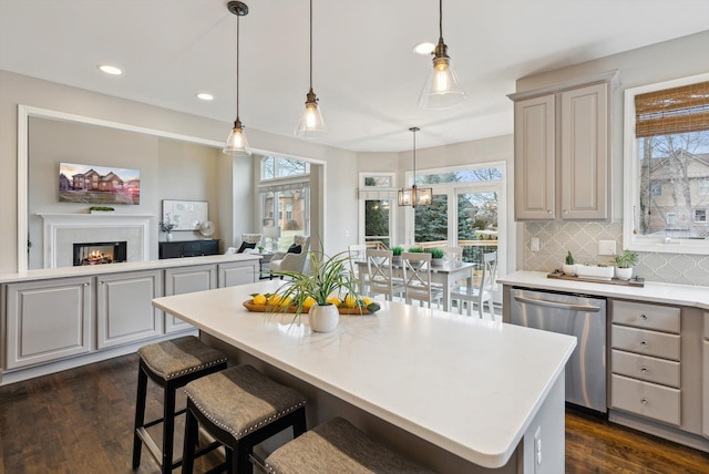 kitchen with pendant lighting, dishwasher, decorative backsplash, gray cabinets, and a kitchen island