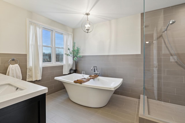 bathroom with a notable chandelier, tile patterned floors, vanity, independent shower and bath, and tile walls