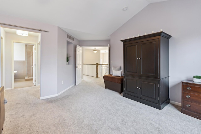 carpeted bedroom with ensuite bathroom and lofted ceiling