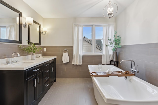 bathroom with vanity, a bath, tile patterned flooring, tile walls, and a notable chandelier