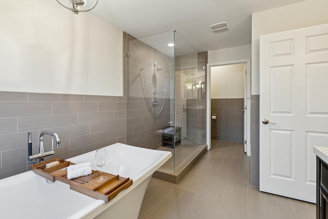 bathroom featuring tile patterned flooring, vanity, shower with separate bathtub, and tile walls