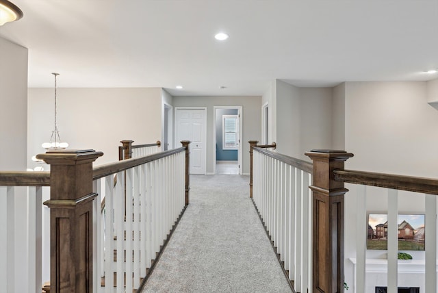 hallway featuring light carpet and an inviting chandelier