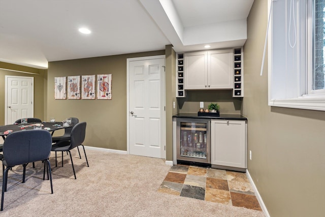 bar with light carpet, white cabinetry, and wine cooler