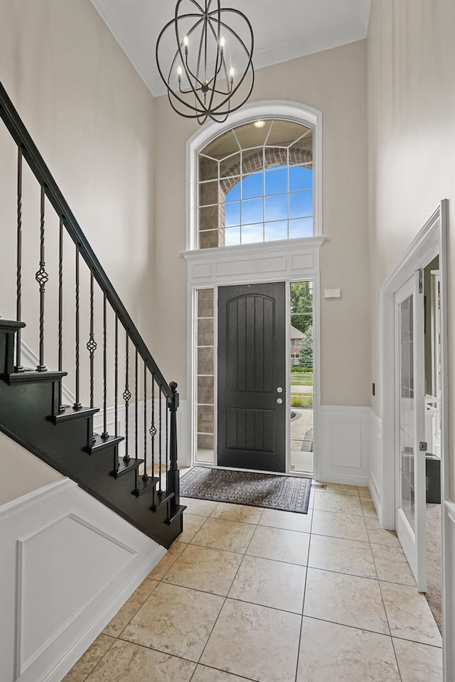 tiled entrance foyer with french doors, an inviting chandelier, and ornamental molding