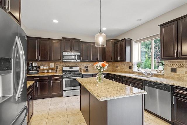 kitchen featuring appliances with stainless steel finishes, dark brown cabinets, sink, decorative light fixtures, and a kitchen island