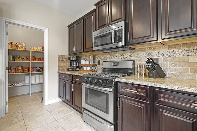 kitchen with backsplash, light stone countertops, light tile patterned floors, dark brown cabinetry, and stainless steel appliances