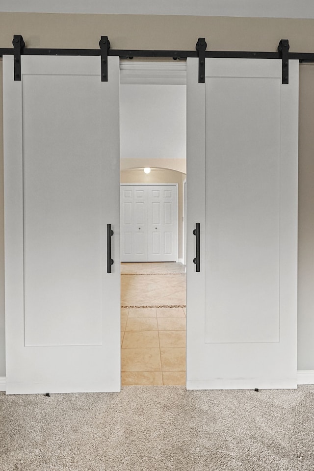 interior space featuring a barn door and light tile patterned flooring