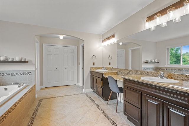 bathroom featuring tile patterned floors, vanity, and tiled bath