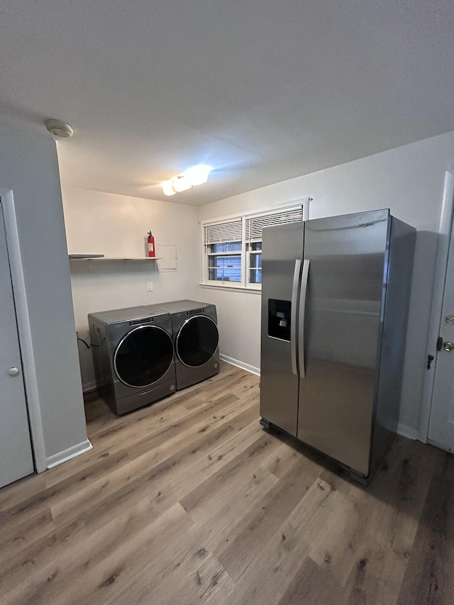 laundry area featuring washing machine and dryer and light hardwood / wood-style floors