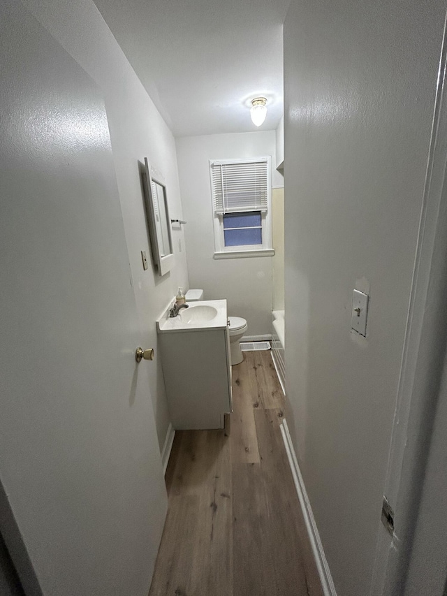 bathroom with a shower, vanity, wood-type flooring, and toilet