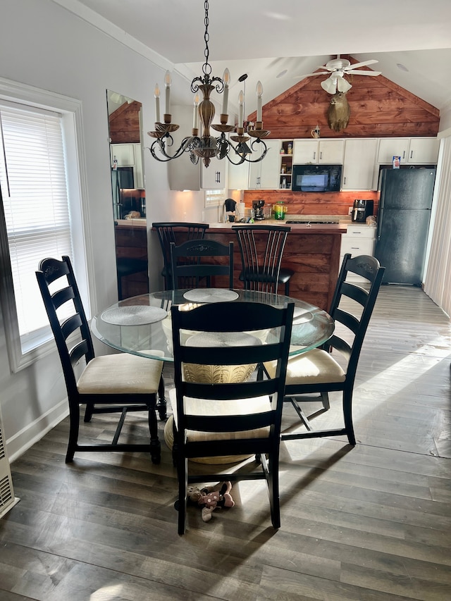 dining space featuring ceiling fan with notable chandelier, dark hardwood / wood-style flooring, and lofted ceiling