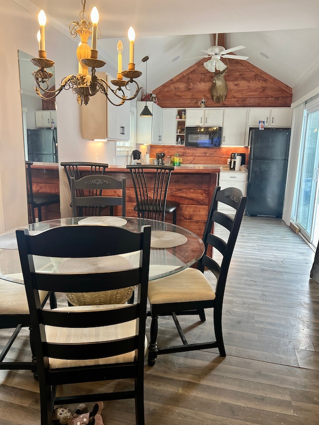 dining space with hardwood / wood-style flooring, ceiling fan with notable chandelier, and lofted ceiling