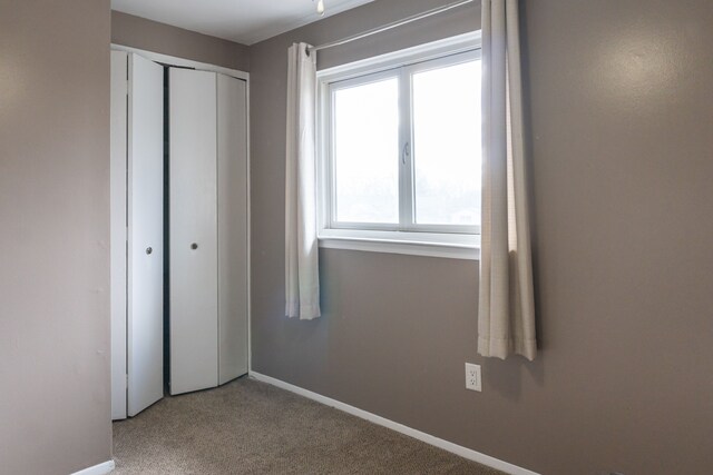 unfurnished bedroom with light carpet, a closet, and multiple windows