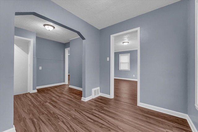 empty room featuring wood-type flooring and a textured ceiling