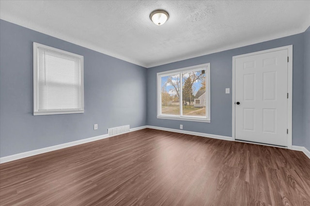 unfurnished room with wood-type flooring and a textured ceiling