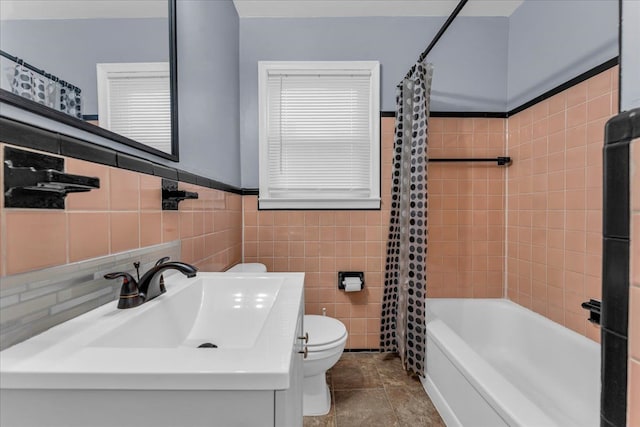 full bathroom featuring sink, shower / bath combination with curtain, tile walls, and toilet