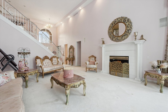 carpeted living room with a fireplace, a towering ceiling, and an inviting chandelier