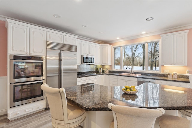 kitchen with stainless steel appliances, white cabinetry, a breakfast bar area, and sink