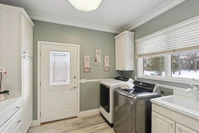 laundry area with washing machine and dryer, cabinet space, light wood-style floors, and ornamental molding