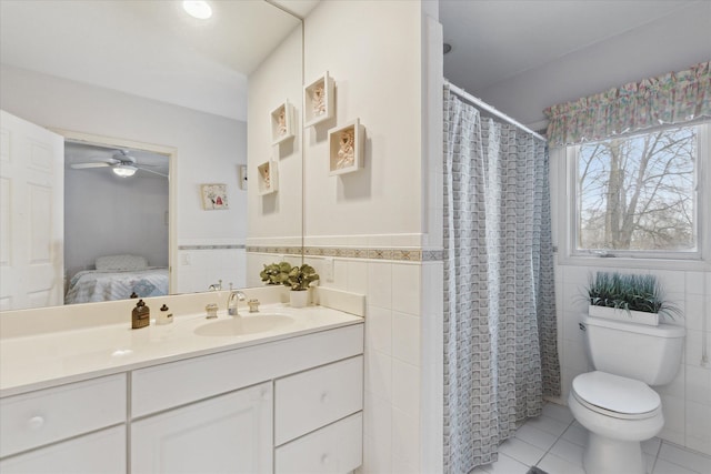 bathroom featuring tile patterned floors, walk in shower, vanity, ceiling fan, and tile walls