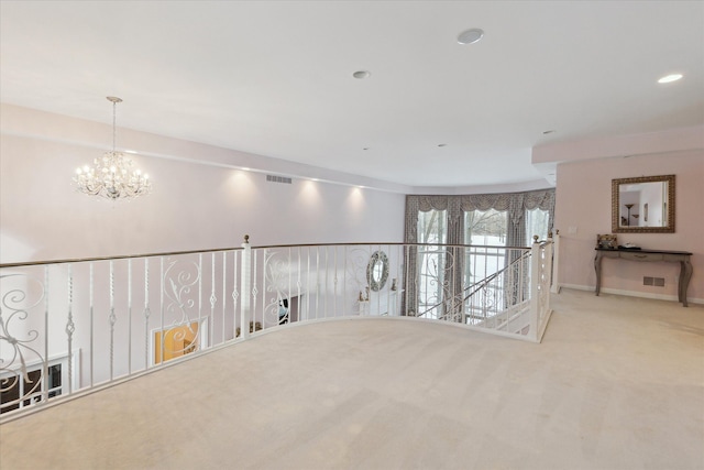 spare room with light colored carpet and a notable chandelier