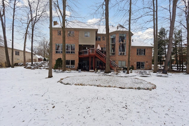 snow covered rear of property featuring a deck