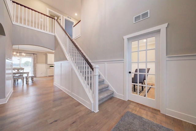 stairway with a chandelier, a high ceiling, and hardwood / wood-style flooring