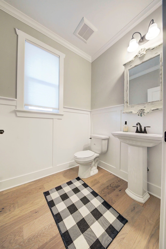 bathroom featuring crown molding, wood-type flooring, and toilet