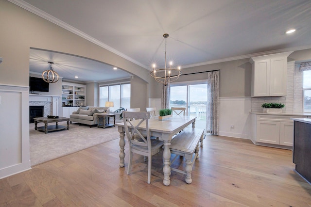 dining area with crown molding, light hardwood / wood-style floors, and an inviting chandelier