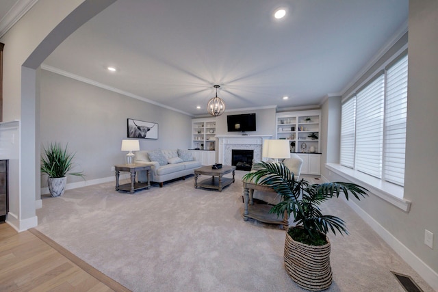 living room with built in shelves, light hardwood / wood-style floors, a healthy amount of sunlight, and a premium fireplace