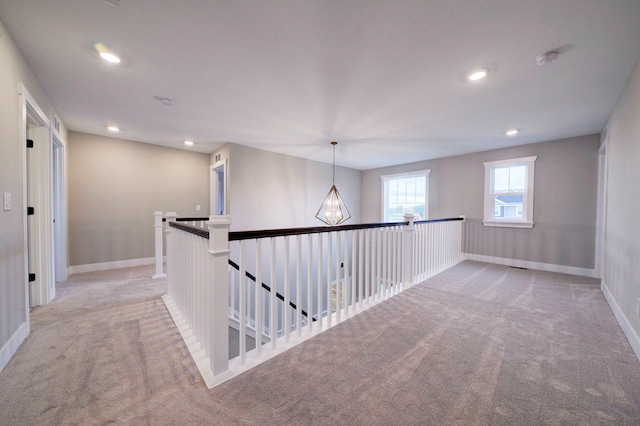 hallway featuring light carpet and an inviting chandelier