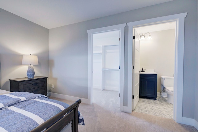 bedroom featuring a walk in closet, connected bathroom, light colored carpet, and a closet