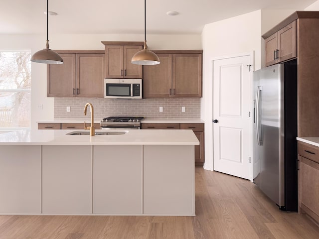 kitchen with pendant lighting, sink, light hardwood / wood-style flooring, and stainless steel appliances