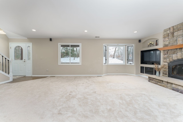 unfurnished living room featuring a fireplace, carpet flooring, built in features, and a healthy amount of sunlight