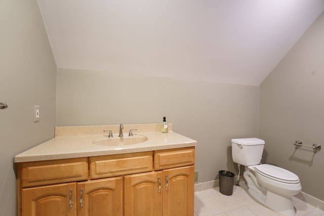 bathroom with toilet, vanity, vaulted ceiling, and tile patterned flooring