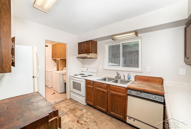 kitchen with white appliances, independent washer and dryer, light countertops, under cabinet range hood, and a sink