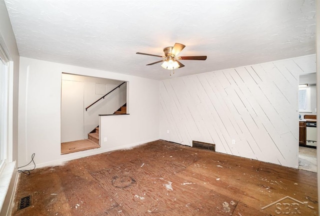 unfurnished living room featuring stairs, ceiling fan, wood finished floors, and visible vents