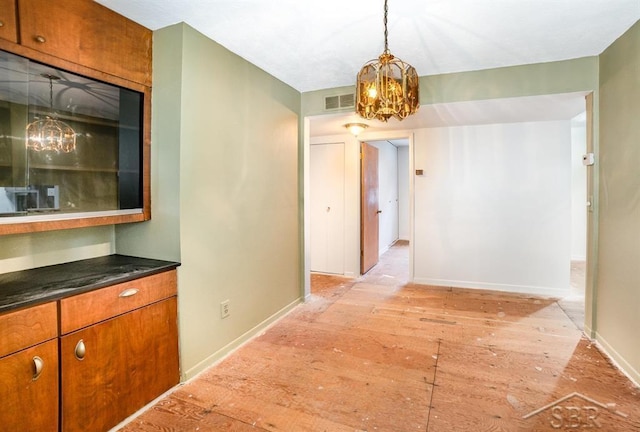 corridor featuring baseboards, visible vents, light wood-style flooring, and a notable chandelier