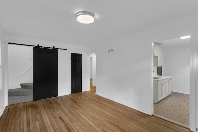 unfurnished room featuring a barn door and light hardwood / wood-style floors