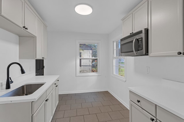 kitchen with white cabinets, dark tile patterned flooring, and sink