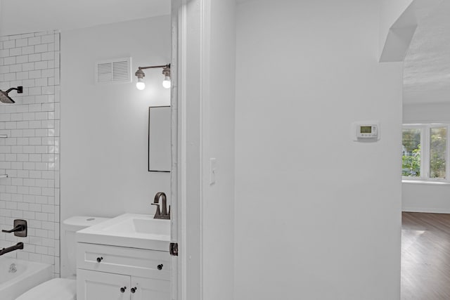 full bathroom featuring vanity, tiled shower / bath combo, and toilet